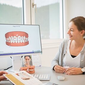 Zahnärztliche Beratung zu Invisalign mit 3D-Visualisierung der Zahnkorrektur am Bildschirm.